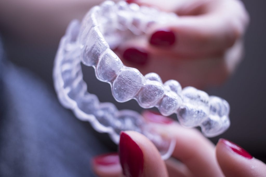 cropped hand woman holding dental aligner