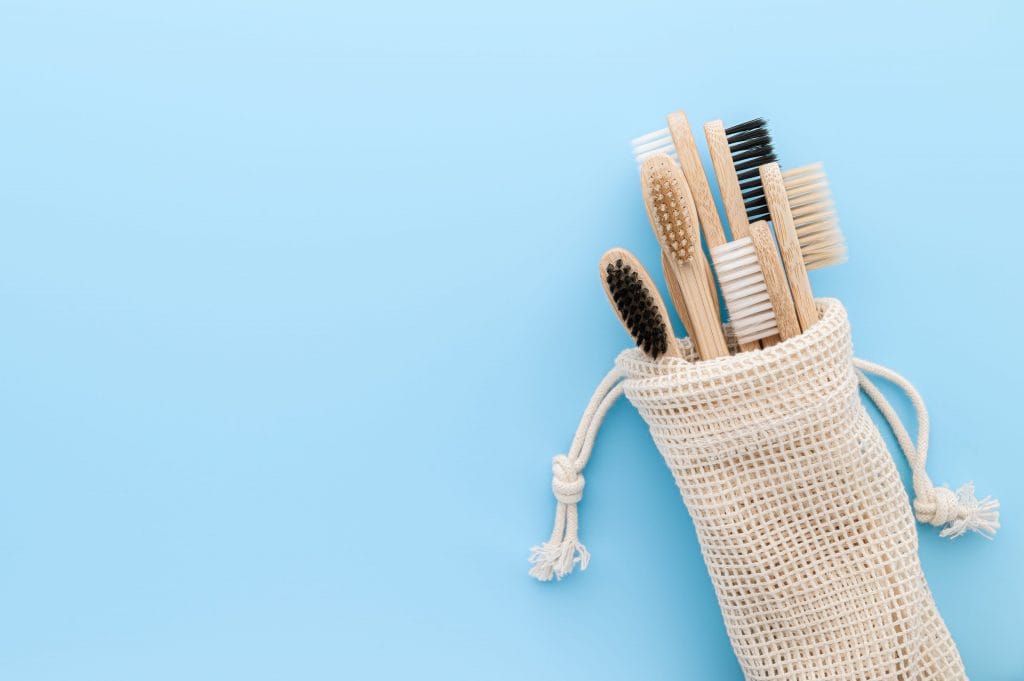 zero waste concept set eco natural bamboo toothbrushes cotton bag light blue background